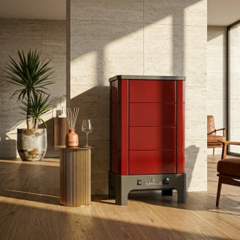 Poêle radiant électrique E40 SL La Valmarecchia en céramique bordeaux dans un salon chaleureux