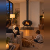 Poêle à bois INVICTA BRIO allumé dans un salon familial un soir d'hiver, sur plaque de protection